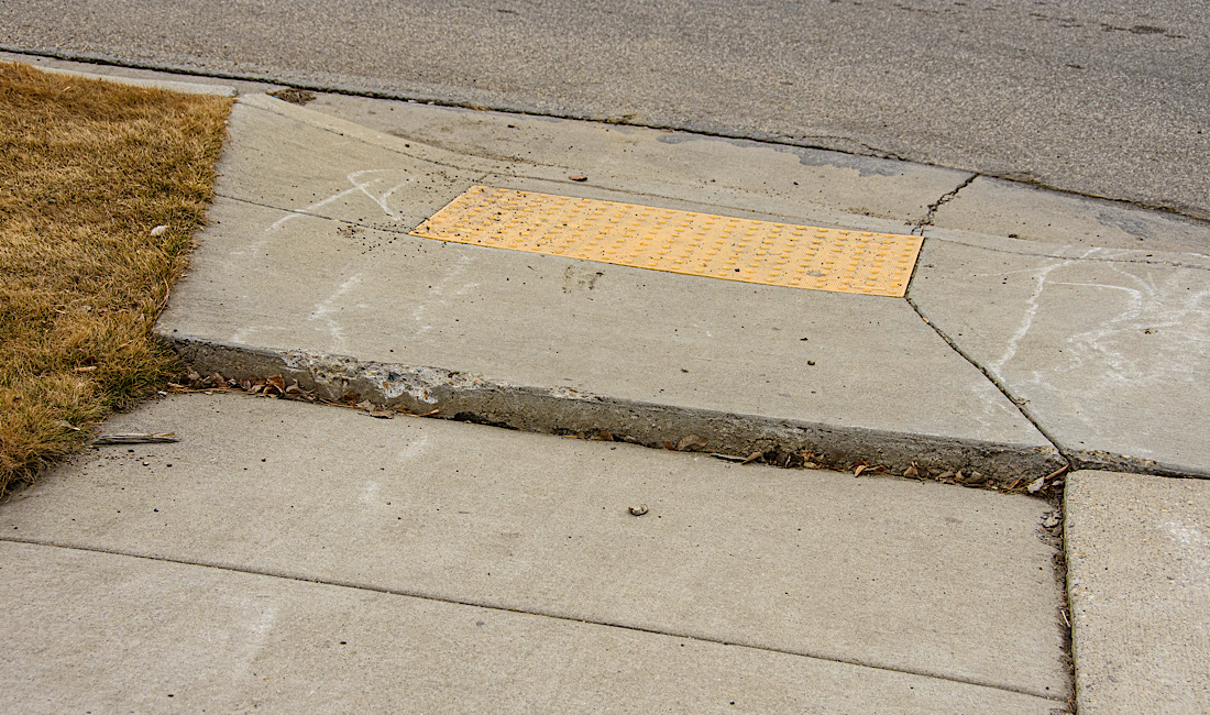 Uneven concrete sidewalk from shifting ground creating trip hazard for pedestrians in Idaho